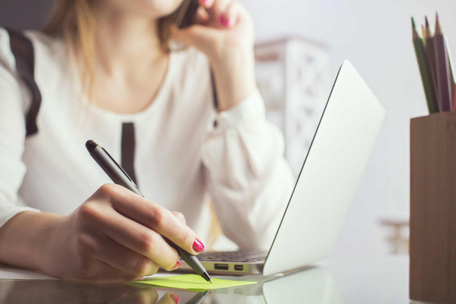 Woman on phone writing memo